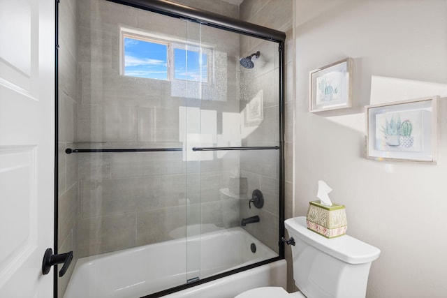 bathroom featuring toilet and combined bath / shower with glass door