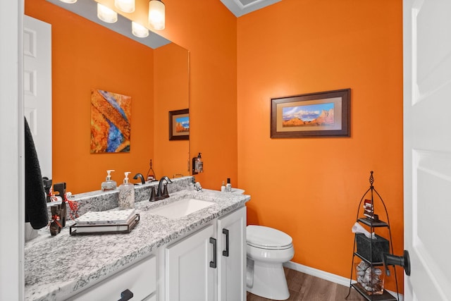 bathroom featuring toilet, baseboards, wood finished floors, and vanity