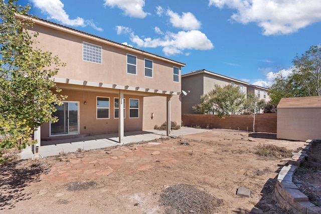 back of property with a storage shed and a patio