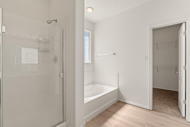 bathroom featuring wood-type flooring, independent shower and bath, and a textured ceiling