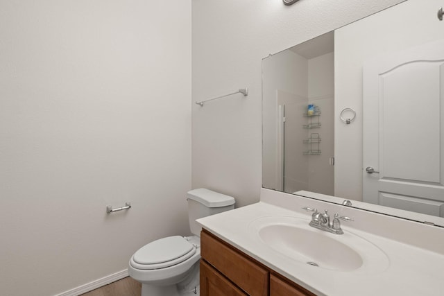 bathroom with toilet, wood-type flooring, vanity, and a shower with shower door