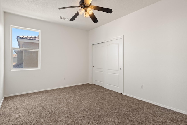 unfurnished bedroom featuring ceiling fan, carpet flooring, a textured ceiling, and a closet