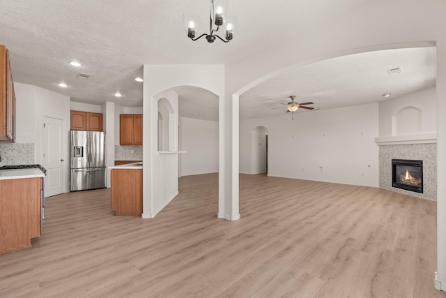 kitchen featuring backsplash, decorative light fixtures, stainless steel fridge, and ceiling fan with notable chandelier