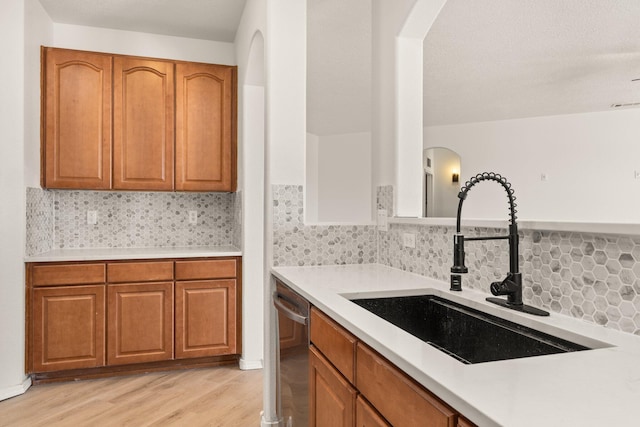 kitchen featuring tasteful backsplash, sink, light hardwood / wood-style floors, and dishwasher