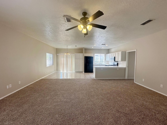 unfurnished living room featuring ceiling fan with notable chandelier, light colored carpet, and a textured ceiling