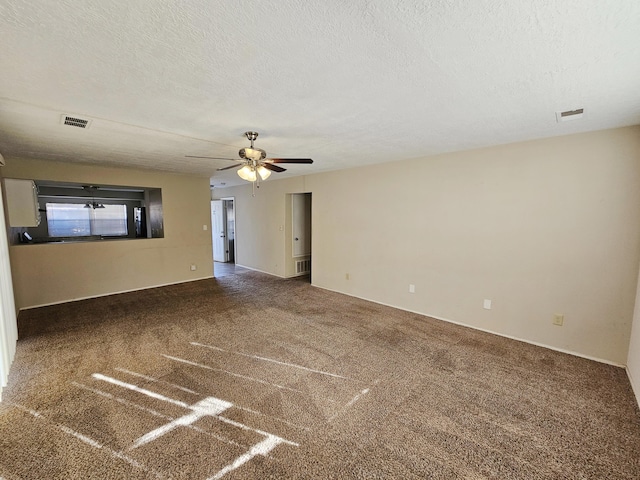 empty room featuring ceiling fan, dark carpet, and a textured ceiling