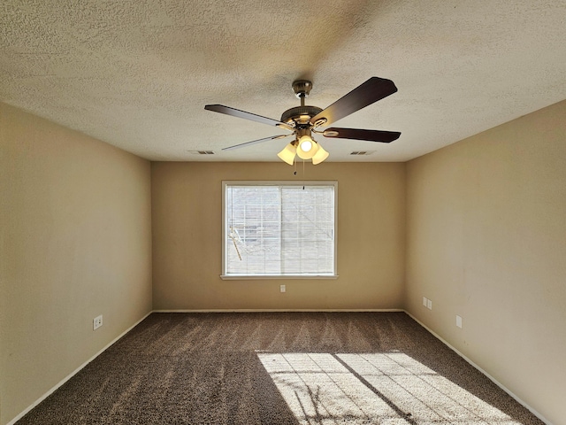 spare room with ceiling fan, dark carpet, and a textured ceiling