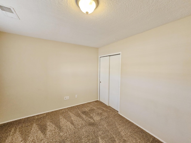 unfurnished bedroom featuring carpet flooring, a textured ceiling, and a closet