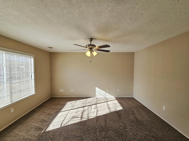 empty room featuring dark colored carpet, a textured ceiling, and ceiling fan