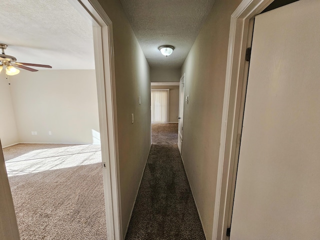 corridor with light colored carpet and a textured ceiling