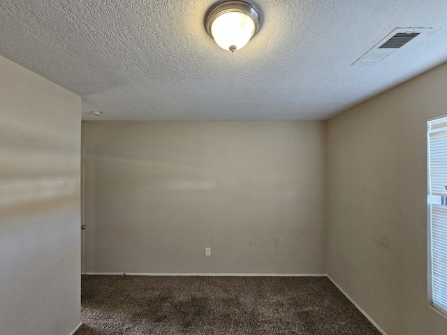 spare room with a textured ceiling and dark carpet