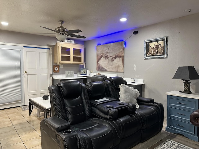 tiled home theater room featuring a textured ceiling and ceiling fan