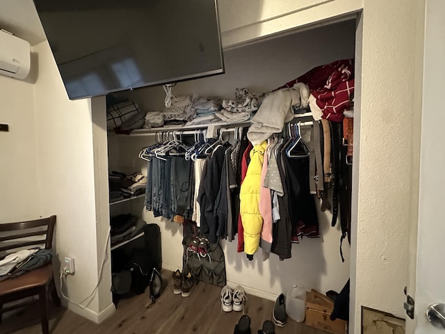 walk in closet featuring hardwood / wood-style floors and an AC wall unit