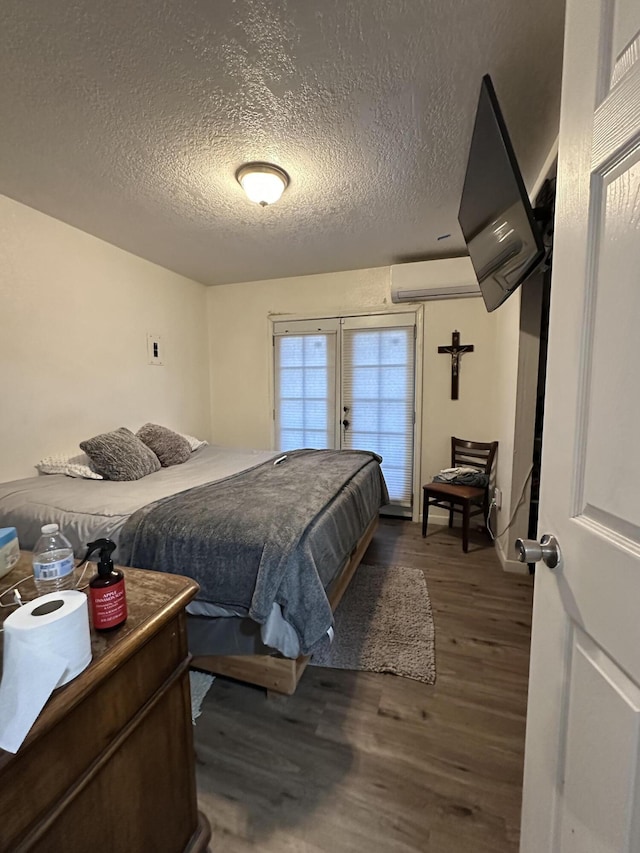 bedroom with french doors, a textured ceiling, dark hardwood / wood-style floors, and an AC wall unit