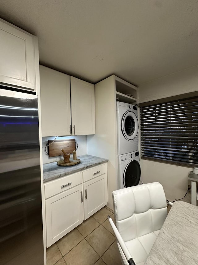 clothes washing area featuring light tile patterned floors and stacked washer and clothes dryer