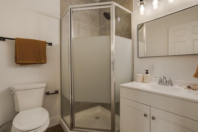 bathroom featuring a shower with door, vanity, and toilet