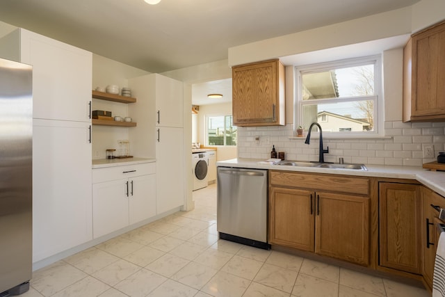 kitchen with washer / clothes dryer, a healthy amount of sunlight, sink, and stainless steel appliances