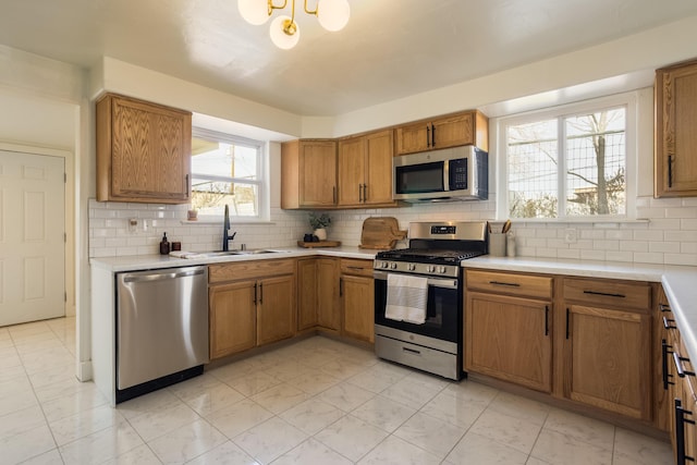 kitchen with decorative backsplash, appliances with stainless steel finishes, light tile patterned flooring, and sink