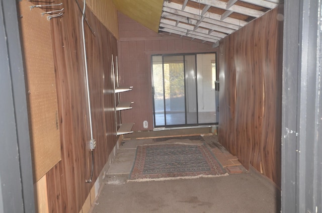 corridor featuring vaulted ceiling and wood walls