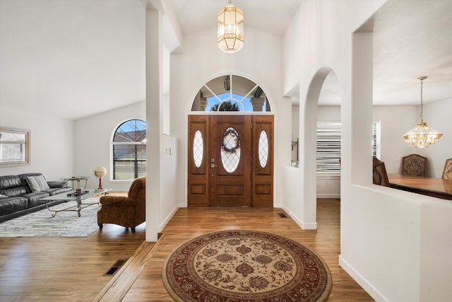 entrance foyer featuring a notable chandelier, light hardwood / wood-style floors, and vaulted ceiling