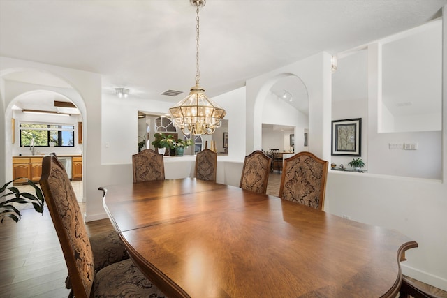 dining area with wood-type flooring and an inviting chandelier