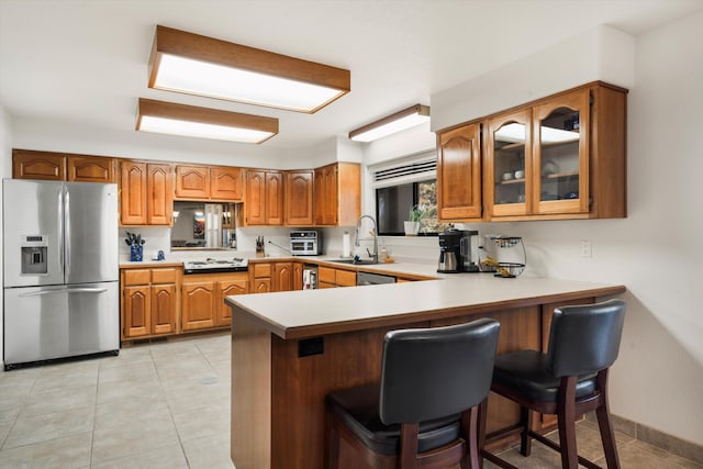 kitchen with white gas stovetop, sink, kitchen peninsula, a kitchen bar, and stainless steel fridge with ice dispenser