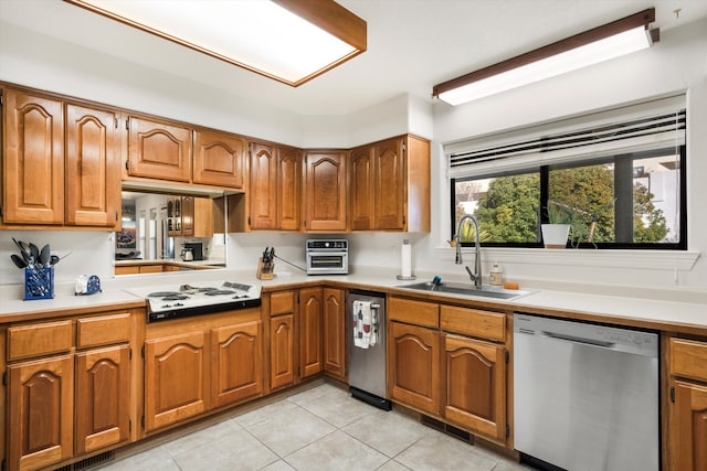 kitchen featuring stainless steel dishwasher, white gas cooktop, light tile patterned floors, and sink