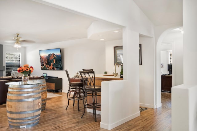 bar featuring ceiling fan, light hardwood / wood-style floors, sink, and vaulted ceiling