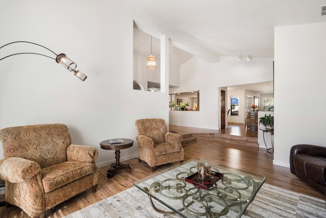 living room with a chandelier, wood-type flooring, and vaulted ceiling with beams