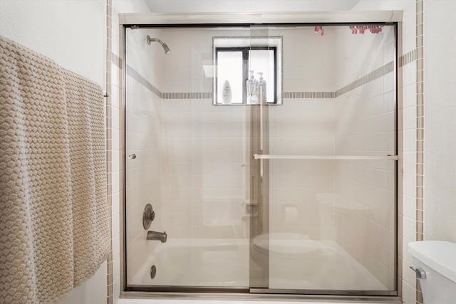 bathroom featuring shower / bath combination with glass door and toilet