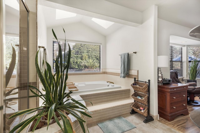 bathroom with tile patterned flooring, tiled tub, and vaulted ceiling