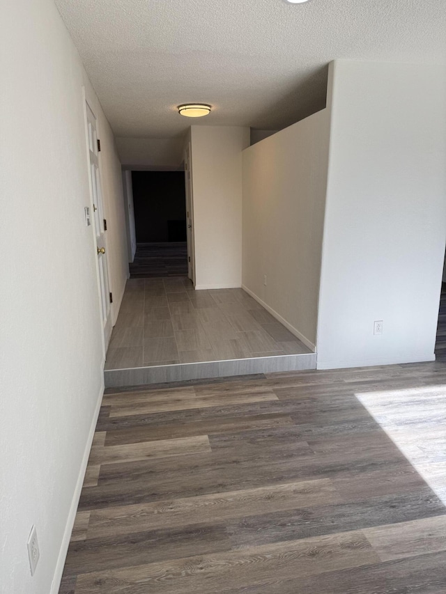 corridor with dark hardwood / wood-style floors and a textured ceiling