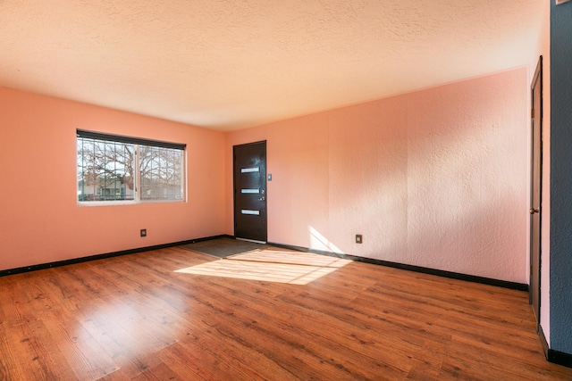 spare room featuring hardwood / wood-style floors and a textured ceiling