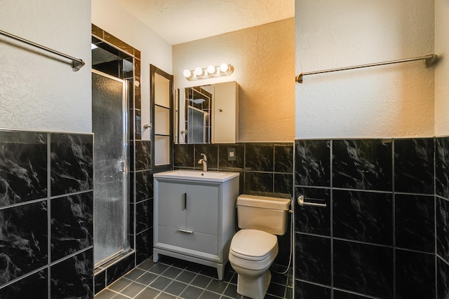 bathroom with tile patterned floors, an enclosed shower, toilet, vanity, and tile walls