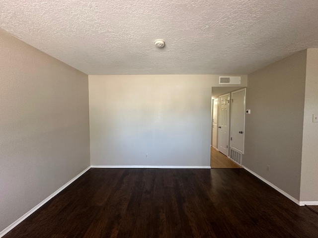 empty room with dark hardwood / wood-style flooring and a textured ceiling