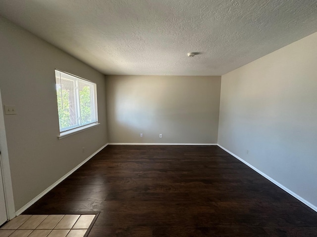 spare room featuring dark wood-type flooring and a textured ceiling