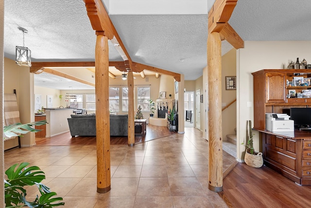 interior space with a textured ceiling, lofted ceiling with beams, and light tile patterned floors