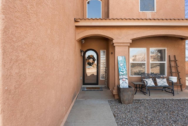 doorway to property featuring a porch and stucco siding
