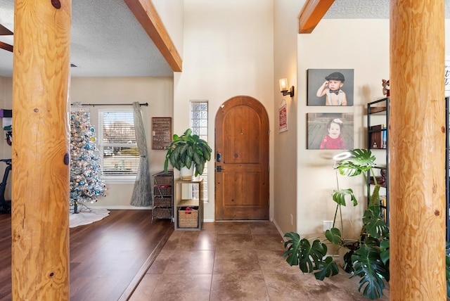 foyer with ornate columns, tile patterned floors, baseboards, and a textured ceiling