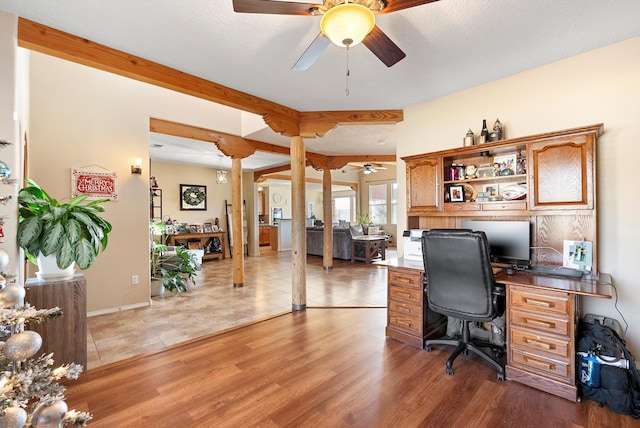 home office featuring light wood-type flooring, beam ceiling, ceiling fan, and a textured ceiling