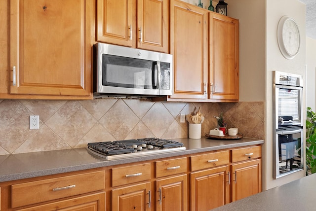 kitchen with appliances with stainless steel finishes, light countertops, and backsplash