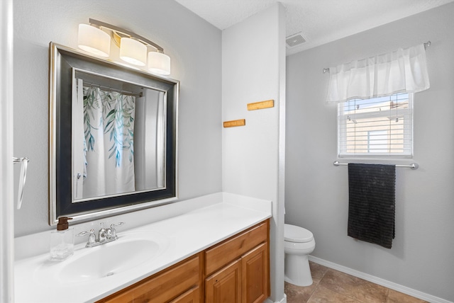 bathroom with visible vents, toilet, vanity, tile patterned flooring, and baseboards