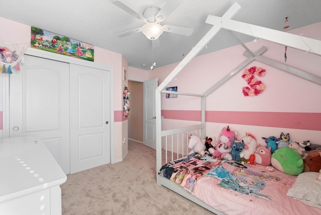 bedroom featuring light colored carpet, a closet, ceiling fan, and a textured ceiling