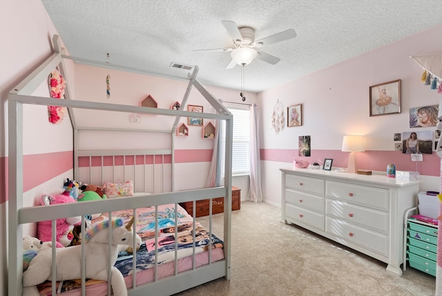 bedroom with ceiling fan, a textured ceiling, light colored carpet, and visible vents