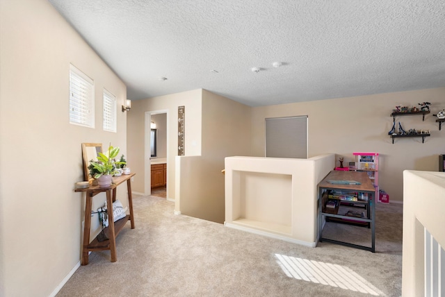 corridor with a textured ceiling, carpet flooring, an upstairs landing, and baseboards