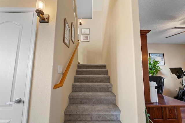 staircase featuring a ceiling fan and a textured ceiling