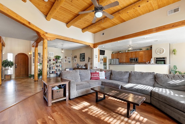 living area with arched walkways, wood ceiling, visible vents, and beamed ceiling