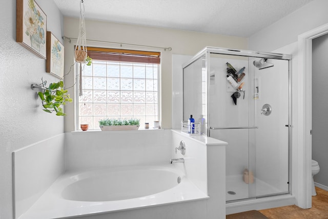 full bath with a stall shower, a textured ceiling, and a bath