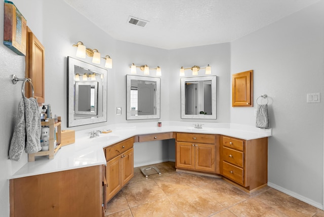 full bath with a textured ceiling, double vanity, a sink, and visible vents