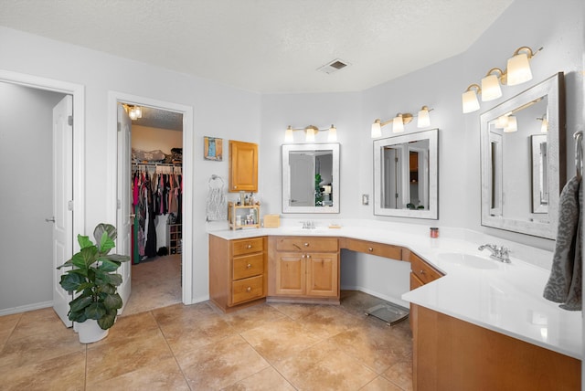 bathroom with double vanity, a textured ceiling, visible vents, and a sink